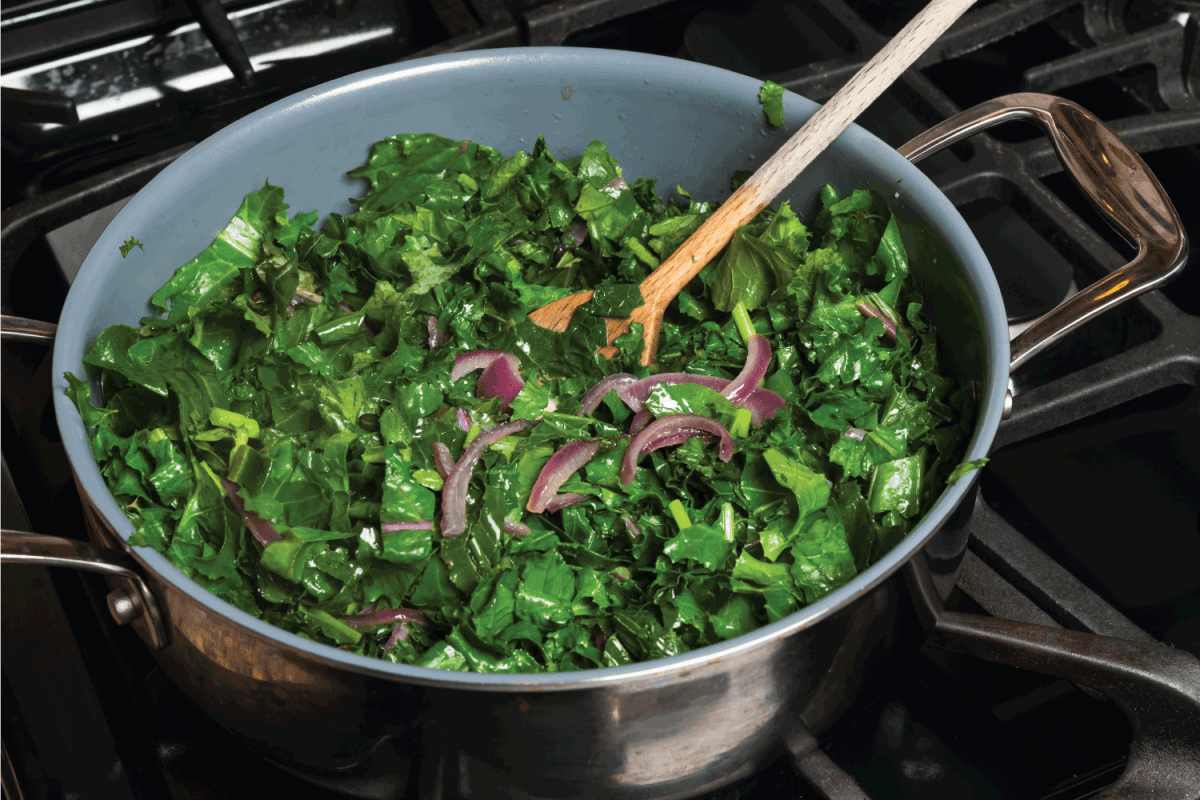 Fresh kale sauteed with onions in a pan on the stove