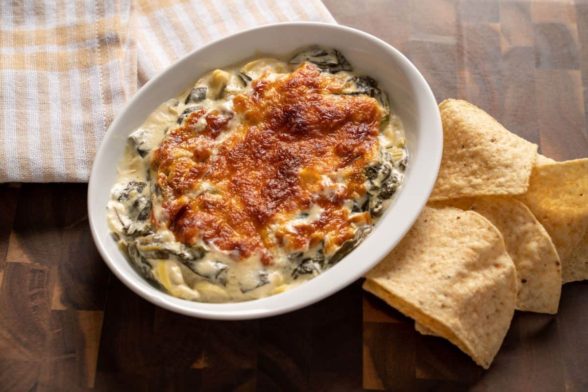 A delicious artichoke dip with cheese and chips on the table