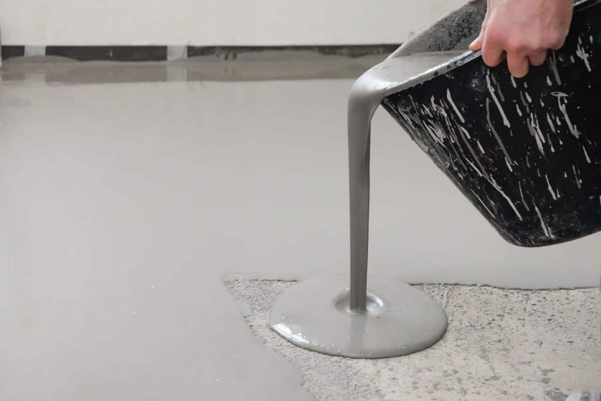 A man pouring self leveling epoxy on the floor
