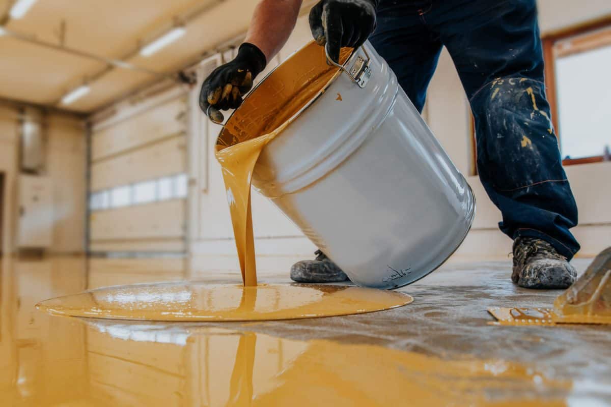 A worker pouring yellow self leveling epoxy on the stadium floor, Will Epoxy Crack In Freezing Weather?