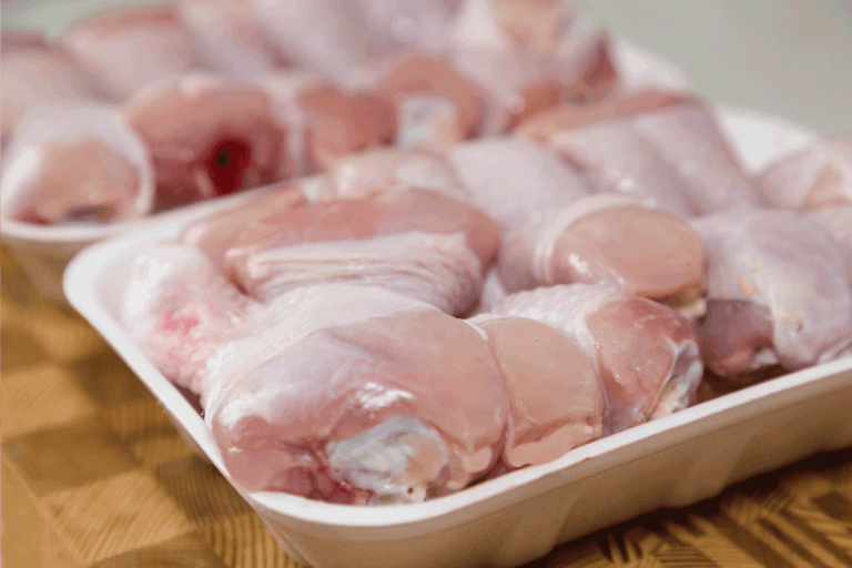 Chicken drumsticks frozen in container on a wooden cutting board. Does Freezing Affect Bleach