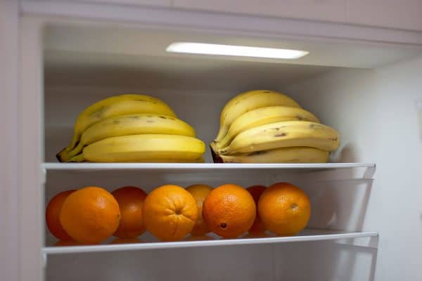 Close-up of bananas and oranges on the shelf in open fridge container, Does Freezing Bananas Ripen Them Or Make Them Sweeter?