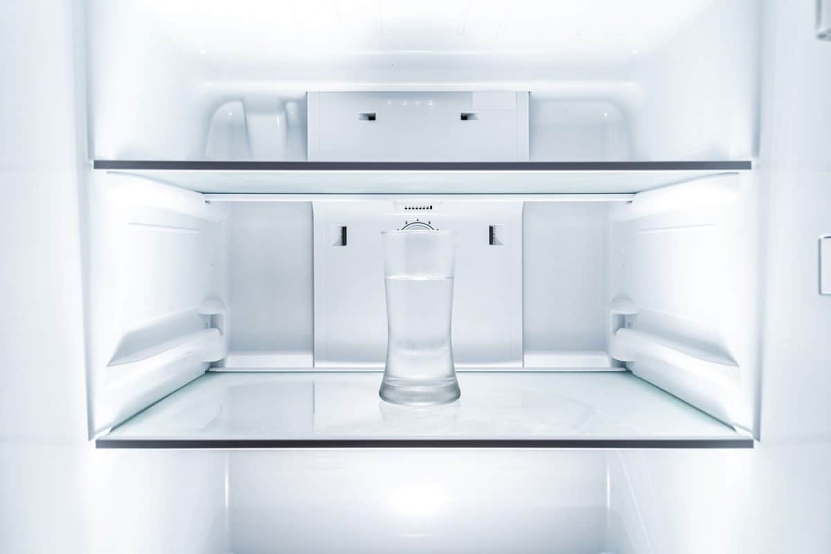 Cold glass of water in clean refrigerator