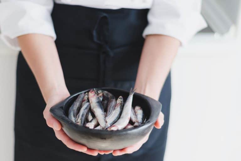 Fresh anchovies in black ceramic bowl over chef's hands, Can You Freeze Anchovies?