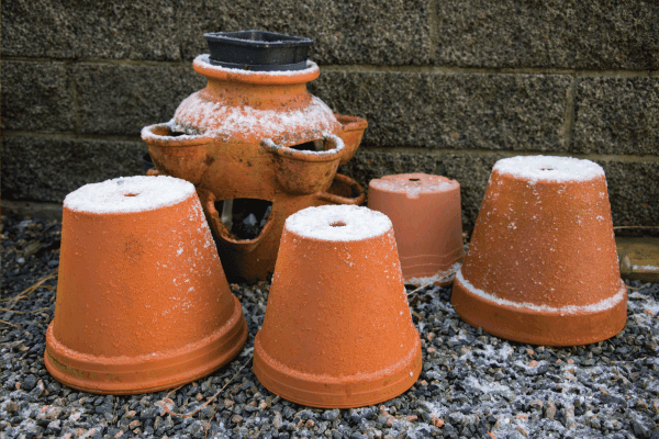 Garden terracotta pots covered in ice and snow. How to Keep Terracotta Pots from Cracking In Freezing Weather