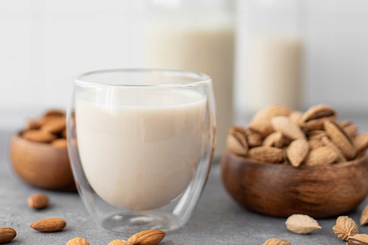 Homemade almond milk in glasses and bottle on table