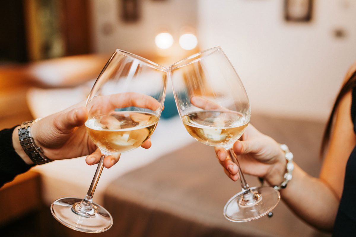 A man and woman toasting a drink of white wine