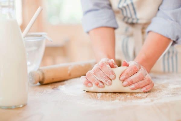 A woman kneading a dough on the large chopping board, How To Thaw Dough Quickly