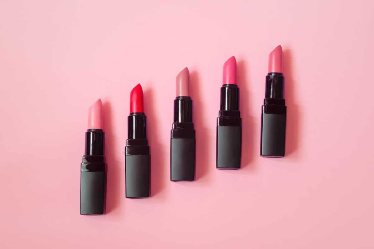 Different shades and colors of lipstick on a pink background