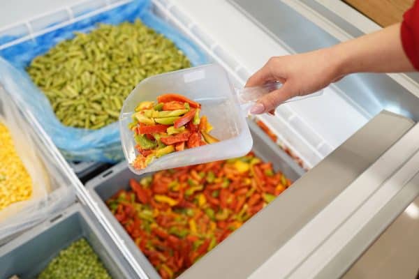 How To Freeze Bell Peppers, Female hand holding frozen pieces of red, green and yellow pepper