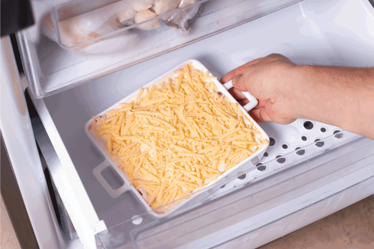 Frozen food. Man's hands are taking frozen casserole from the freezer of the fridge. How Long Will Cheese Last In The Freezer