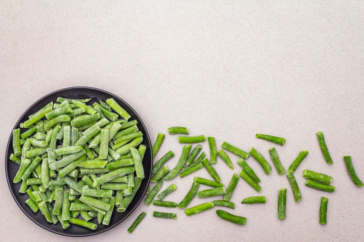 Frozen organic green beans. Healthy food concept, cooking background. In a plate on a stone background, top view, Can You Freeze Uncooked Beans?