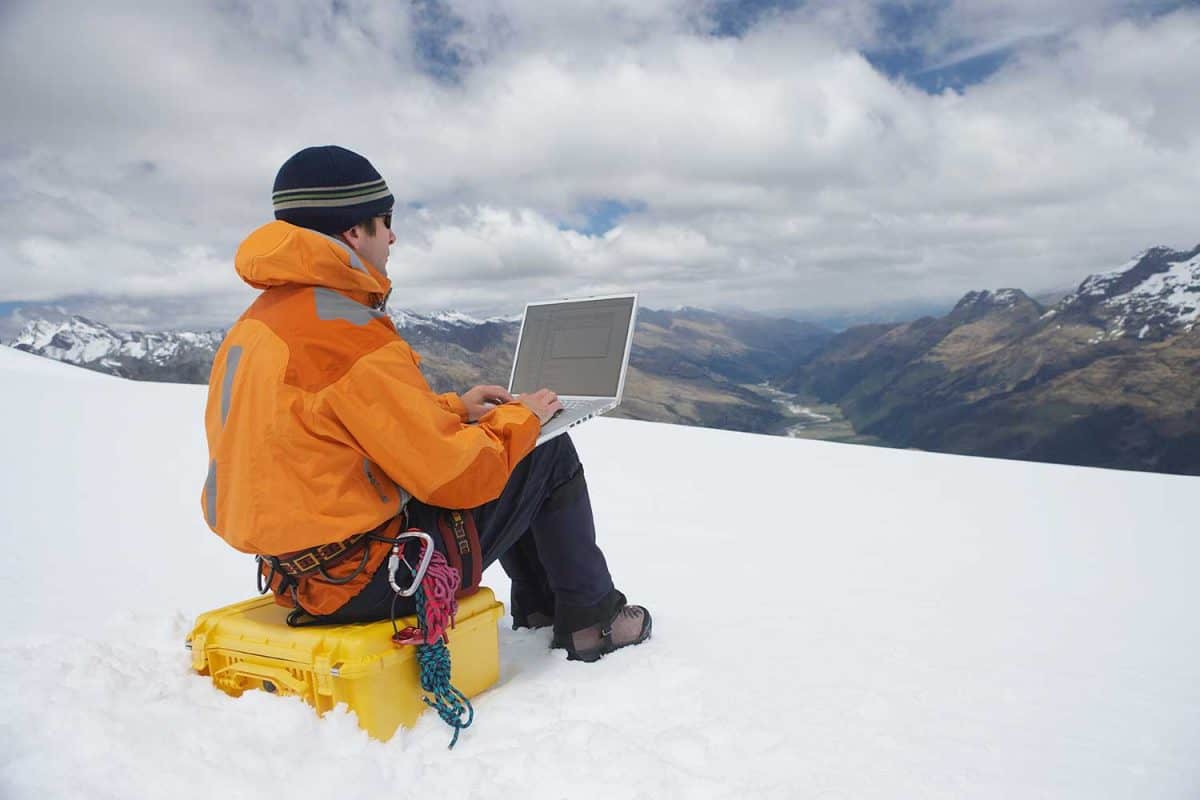Hiker using laptop on mountain