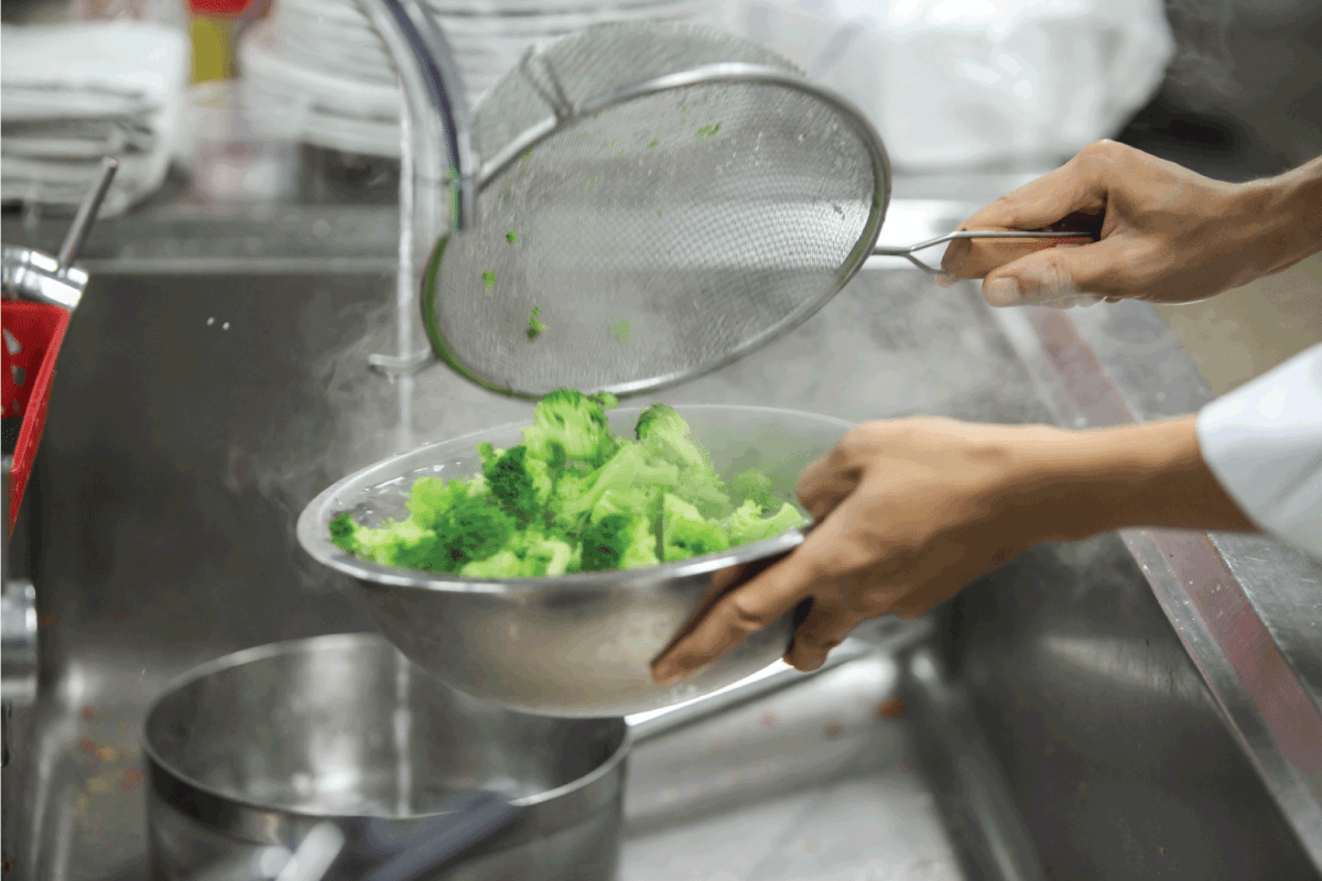 The chef is knocking Broccoli in the cold water in the kitchen.