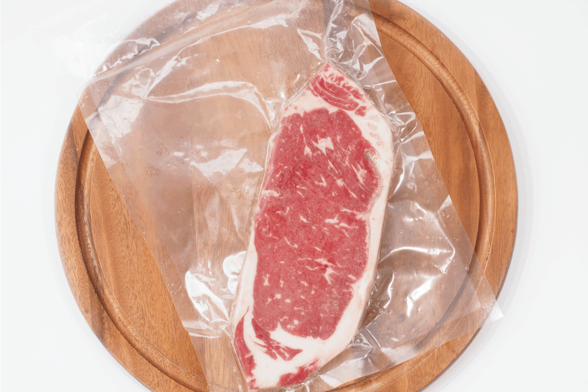 raw striploin beef steak in vacuum seal plastic bag on white background.
