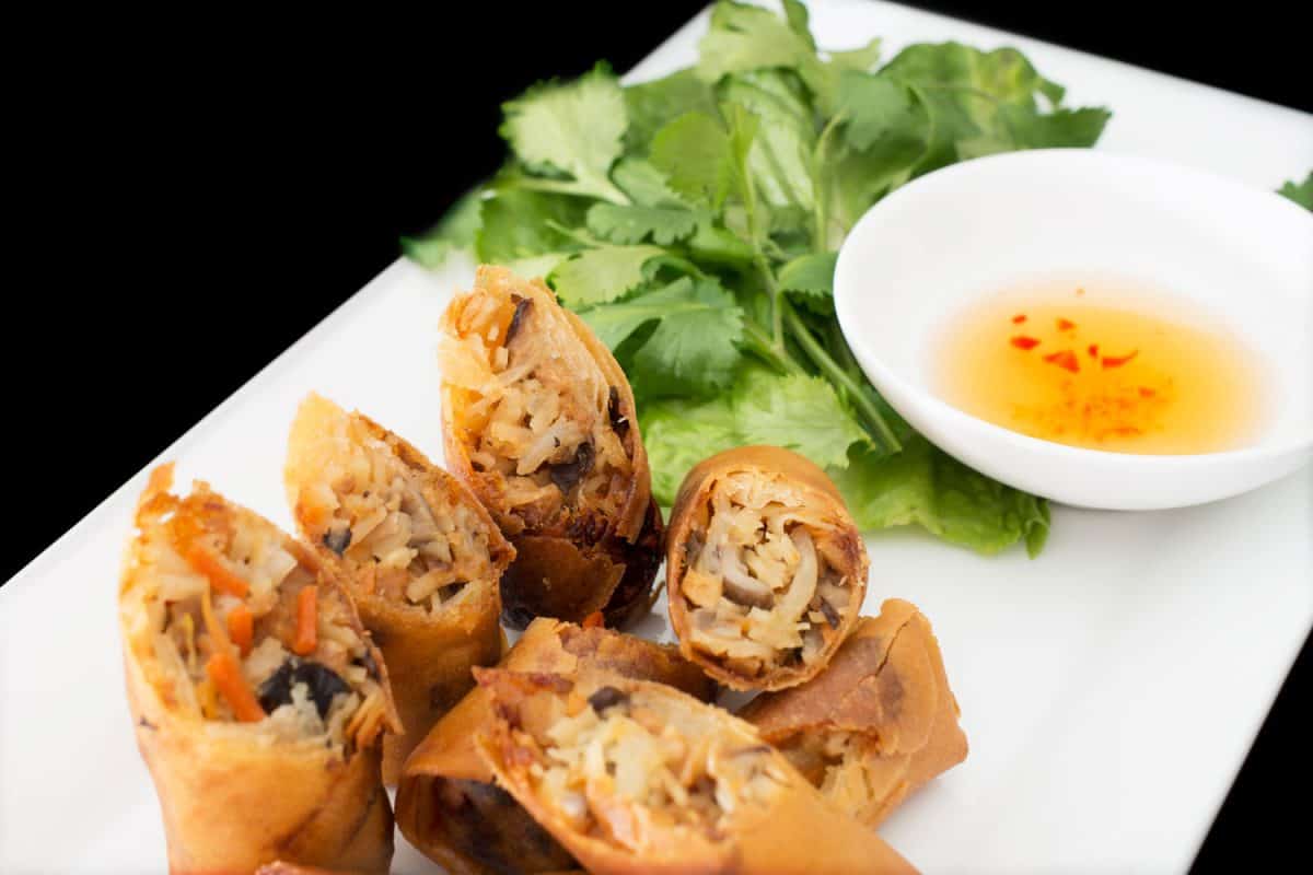 Delicious sliced egg rolls with spinach on the table and sauce on the small saucer