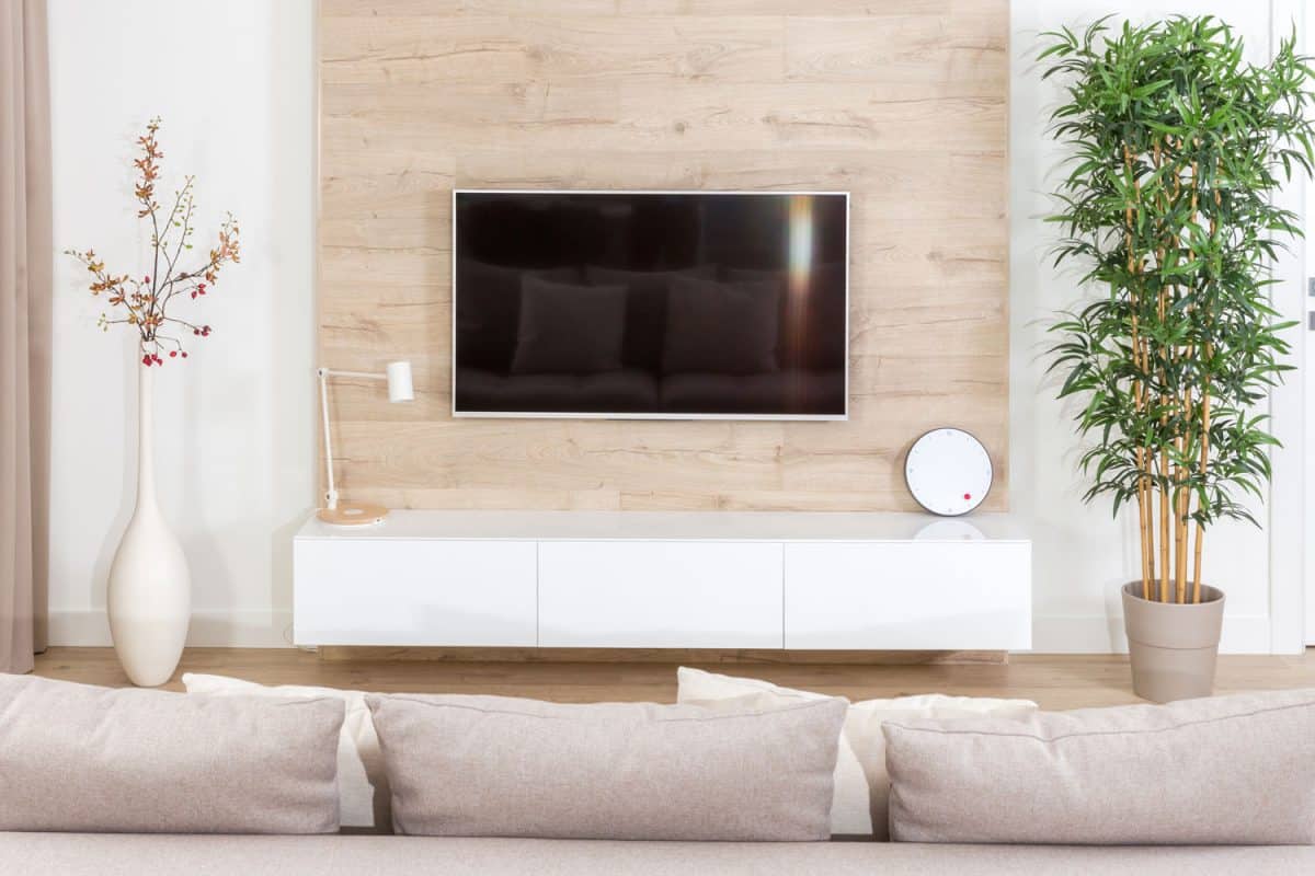 A plasma tv wall mounted on a tv fronting the gray sectional sofa