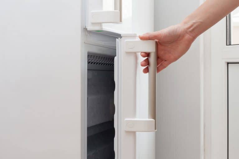 Hand of a young woman is opening a freezer door, How To Reverse A Freezer Door