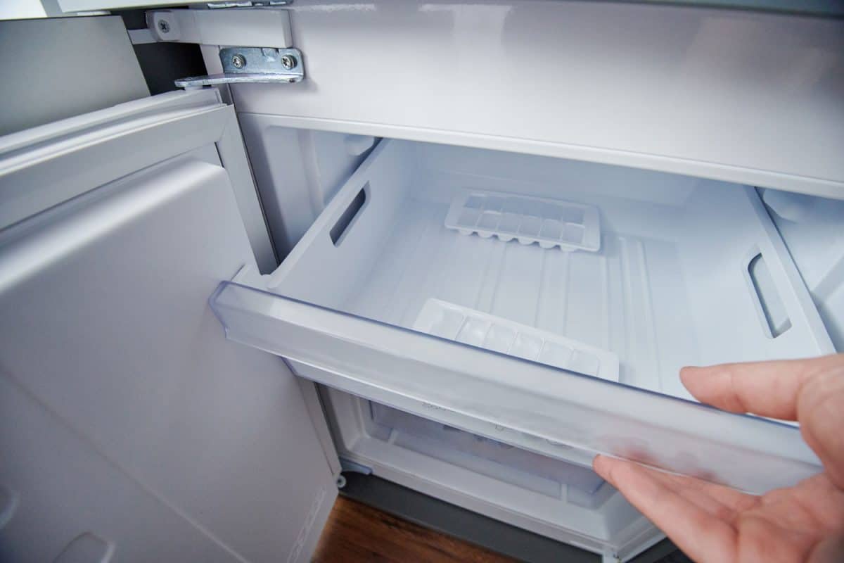 A woman opening the freezer drawer of her refrigerator