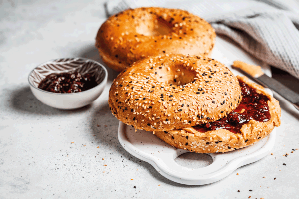 Bagels with peanut butter and berry jam on a white board. Vegan food concept. How To Defrost A Bagel In An Air Fryer