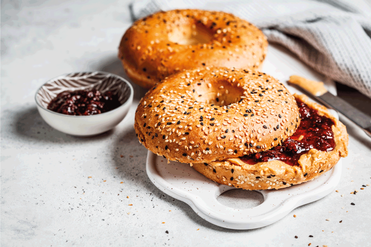 Bagels with peanut butter and berry jam on a white board. Vegan food concept. How To Defrost A Bagel In An Air Fryer