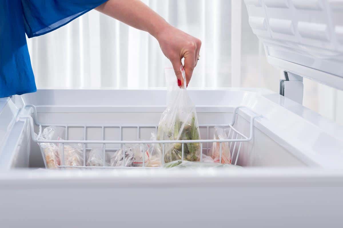 A woman putting some vegetables in the freezer, Why Are Chest Freezers Not Frost Free?