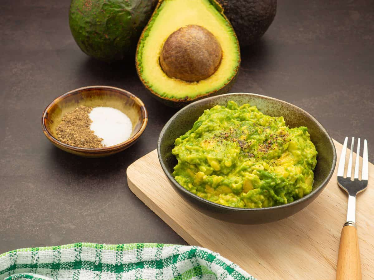 Fresh guacamole on a dish placed on a cutting wooden board