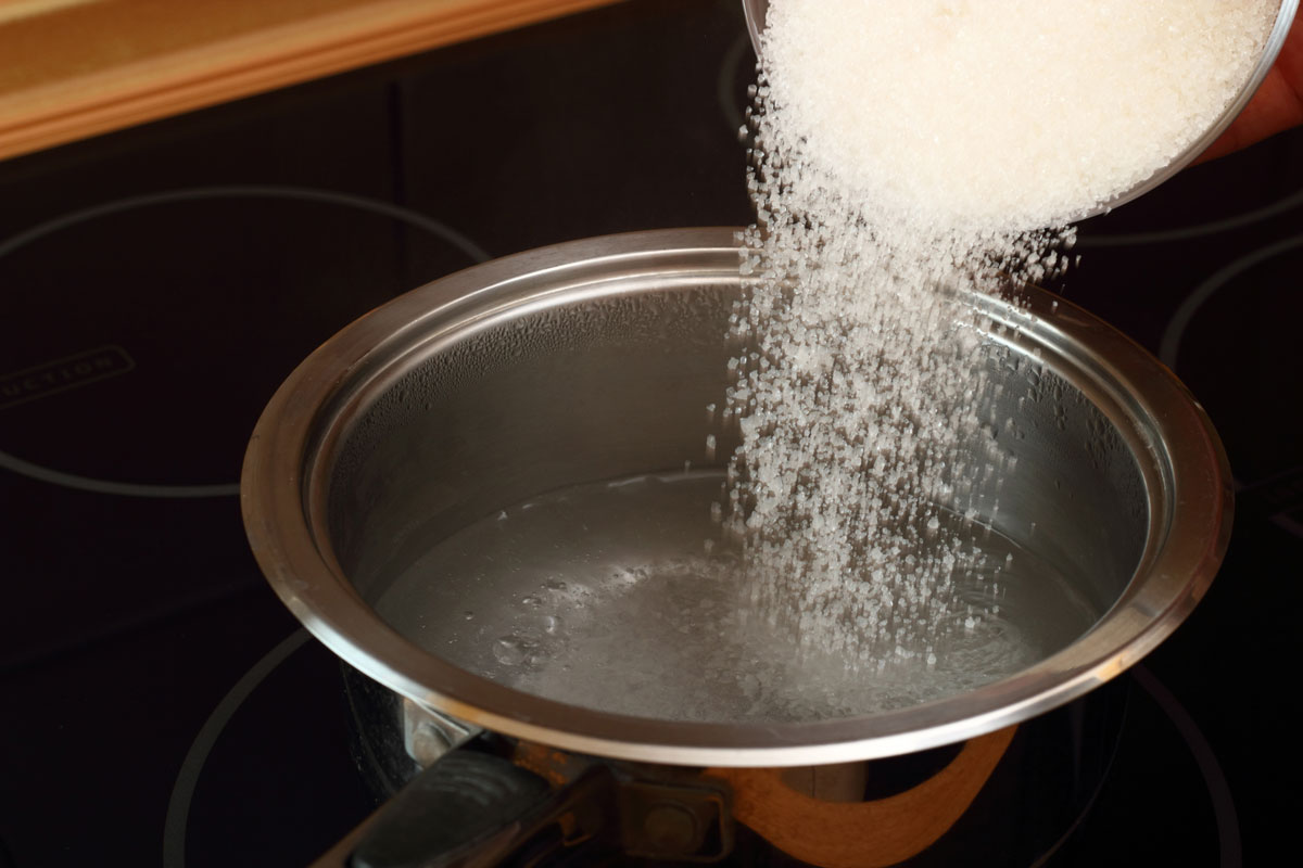 Pouring sugar into a pot of water