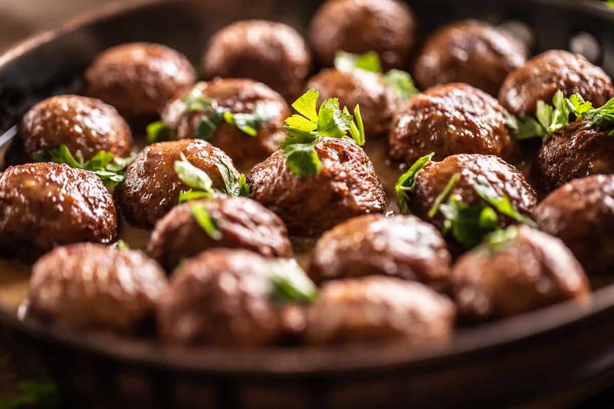 A bowl full of meatballs garnished with parsley