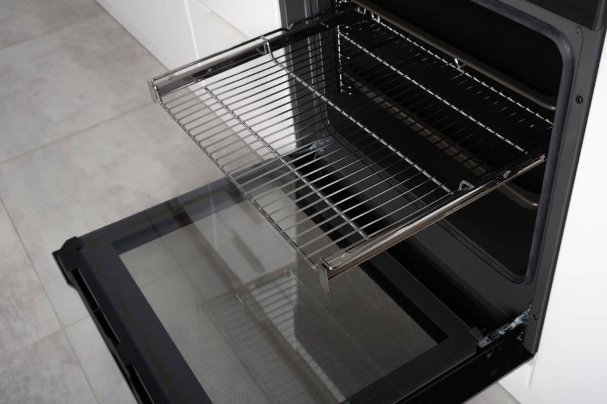 New modern electric oven built in black with screen, convention and grill, empty and open. Telescopic guides. Scandinavian loft style in a white minimalistic kitchen. High quality photo
