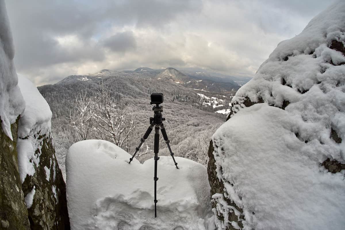 A tripod set up on top of a mountain waiting for a perfect shot