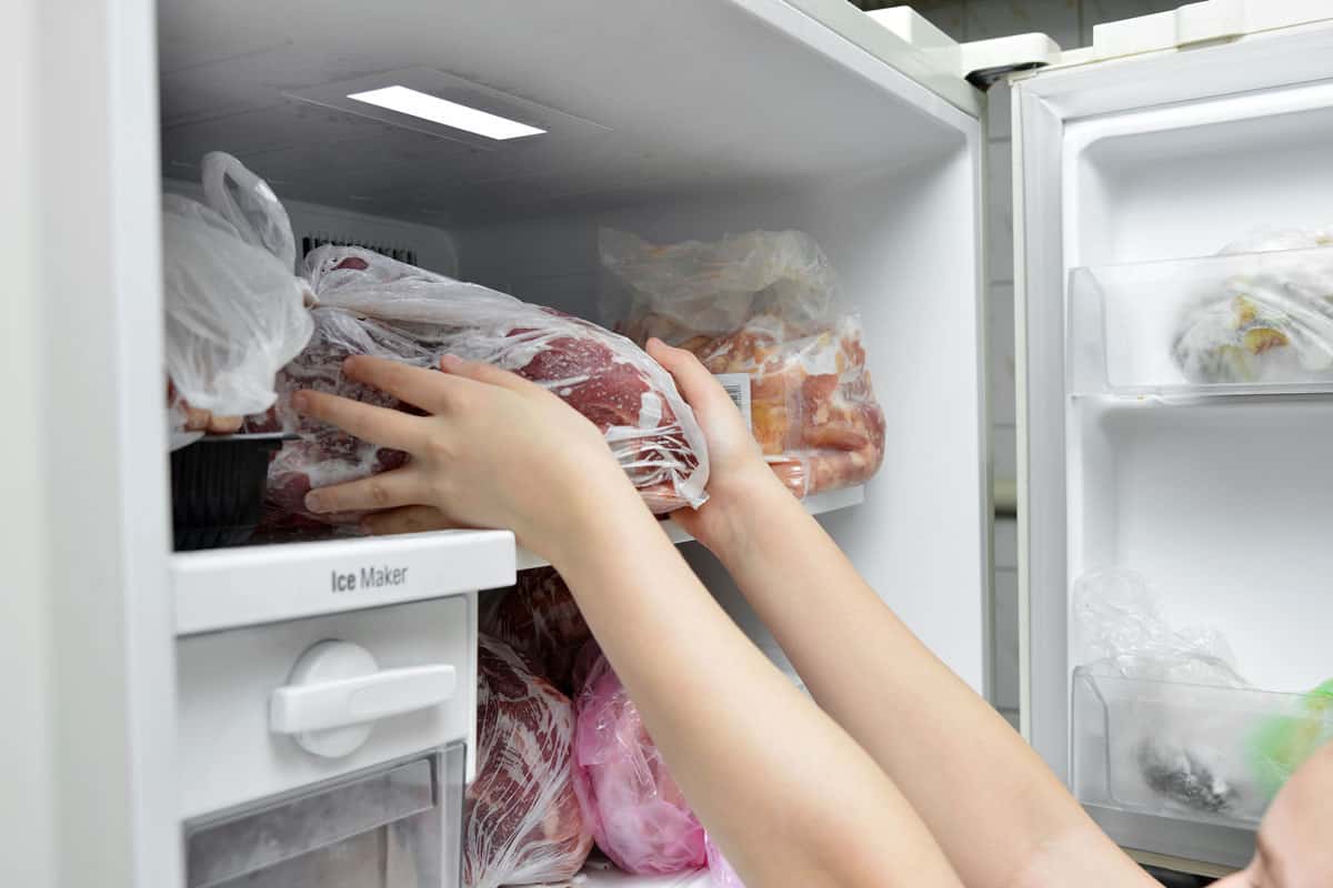 Woman taking frozen meat from the freezer